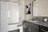 Elegant bathroom featuring sleek granite countertops, a modern vanity, and a stylish bathtub with white subway tiles.
