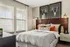 Bright bedroom with stylish decor, featuring a comfortable bed, cozy pillows, and modern wall art.