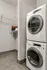 Modern laundry area with a stacked washer and dryer, next to a spacious storage shelf.