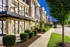 Charming exterior view of a modern apartment complex with well-maintained landscaping and bright evening lighting.