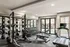Modern gym with weightlifting equipment, treadmill, and outdoor view through large windows.