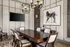 Stylish dining room with a large wooden table, modern chandelier, and art piece depicting a horse on the wall.