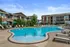 Inviting outdoor pool area at a modern apartment complex with comfortable lounge chairs and vibrant umbrellas.