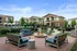 Inviting outdoor patio area with stylish seating and fire pit, surrounded by modern apartment buildings.