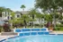 Stunning apartment complex with lush greenery and a sparkling blue pool in the foreground.