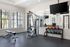 Bright, modern fitness center with weight machine, bench, kettlebells, and large mirror wall.