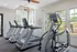 Well-lit apartment fitness room with modern treadmills and an elliptical machine.