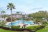 Inviting pool area surrounded by palm trees and modern apartment buildings under a clear sky.