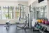 Bright gym space with modern workout equipment, kettlebells, and large windows showcasing a garden view.