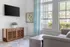 Contemporary living room featuring a stylish gray sofa, wooden console, and artwork bathed in natural light.