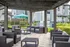 Inviting patio area with modern wicker seating under a wooden pergola, complemented by a barbecue station and lush greenery.