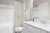 Modern bathroom with white cabinetry, sleek countertop, and shower with a patterned curtain.