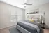 Elegant bedroom with a tufted headboard, plush bedding, modern lamps, and a large window with blinds.