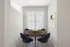 Bright dining nook with a round wooden table and modern blue chairs.