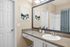 Chic bathroom with a large mirror, granite countertop, and modern artwork above a white cabinet.