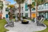 Inviting apartment courtyard featuring Adirondack chairs around a central fire pit, surrounded by palm trees.