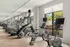 Modern gym with advanced exercise machines and large windows.