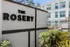 Entrance to The Rosery with modern apartments in the background and lush greenery.