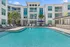 Elegant apartment complex with a sparkling pool, surrounded by palm trees and modern balconies.