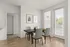 Contemporary dining space with a wooden table, four chairs, and large windows providing natural light.