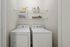 Modern laundry room with Whirlpool washer and dryer, complete with organized shelving and storage solutions.