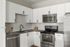 Modern kitchen with sleek stainless steel appliances, white cabinetry, and elegant tile backsplash.