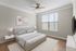 Bright, modern bedroom with stylish furnishings, large window for natural light, and cozy wood flooring.