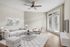 Elegant living room with a modern beige sofa, chic armchair, and stylish coffee table, complemented by a contemporary ceiling fan and natural light from large patio doors.