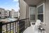 Charming apartment balcony with a cozy chair and table overlooking a pristine pool area and modern residential buildings.