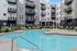 Modern apartment complex with elegant balconies overlooking a luxurious swimming pool and stylish poolside lounging area.