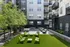 Modern apartment courtyard featuring lush greenery, stylish seating areas, and charming string lights, offering a perfect outdoor retreat.
