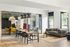 Modern open living area with chic wooden flooring, stylish dining table, and cozy seating, enhanced by large windows for natural light.