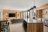 Modern open-concept living and kitchen space with elegant wood accents, large island, and stylish pendant lighting.