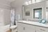 Bright and modern bathroom featuring sleek countertops, elegant lighting, and a stylish patterned shower curtain.