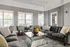 Elegant and bright living area with large windows, stylish grey couches, vibrant yellow decor, and a chic mirrored coffee table.