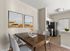 Contemporary open-plan kitchen and dining area featuring sleek stainless steel appliances, a stylish wooden table, and modern artwork.