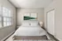 Inviting bedroom with modern decor, plush bedding, and natural light from large windows. Tranquil ambiance enhanced by elegant artwork and soft lighting.