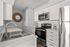 Modern kitchen with sleek stainless steel appliances, white cabinetry, and elegant countertops, featuring a stylish sunburst wall mirror.
