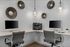 Modern home office setup with dual desktop computers, elegant swivel chairs, and contemporary wall decor, illuminated by stylish pendant lighting.