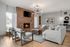 Elegant and modern living room with a cozy fireplace, soft gray seating, contemporary artwork, and a stylish light fixture.