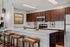 Modern kitchen with elegant dark wood cabinets, sleek stainless steel appliances, and a stylish quartz countertop featuring golden geometric decor pieces.