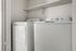 Sleek laundry area with modern washer and dryer set, featuring convenient overhead shelving.