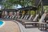 Inviting outdoor lounge area with numerous sun loungers under elegant pergolas, perfect for relaxation by the poolside.
