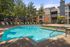 Inviting apartment complex with a sparkling turquoise swimming pool surrounded by lush greenery and comfortable loungers.