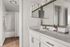 Modern bathroom featuring sleek white vanity with dual mirrors, elegant countertop, and inviting tub with shower.