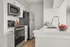 Chic modern kitchen with sleek stainless steel appliances, white cabinetry, and elegant countertops adorned with fresh apples in a cozy corner.