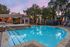 Inviting outdoor pool with tranquil blue waters, surrounded by stylish patio seating and lush trees, perfect for relaxation.