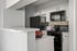 Modern kitchen with sleek black appliances, granite countertops, and stylish mosaic backsplash.