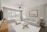 Bright living room featuring elegant couches, a sleek glass coffee table, and modern decor with large windows allowing ample natural light.
