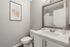Elegant bathroom featuring sleek white cabinetry, modern fixtures, and a tasteful abstract art piece, creating a sophisticated and tranquil ambiance.